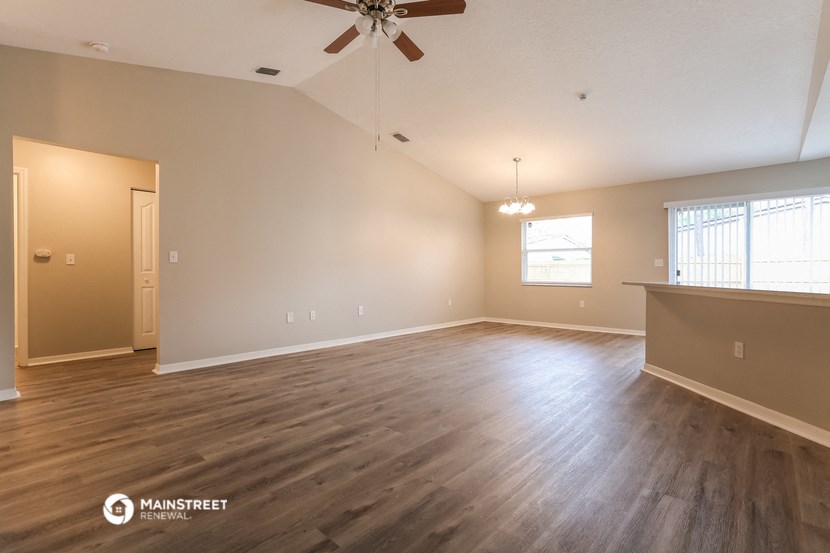 the spacious living room with wood flooring and a ceiling fan