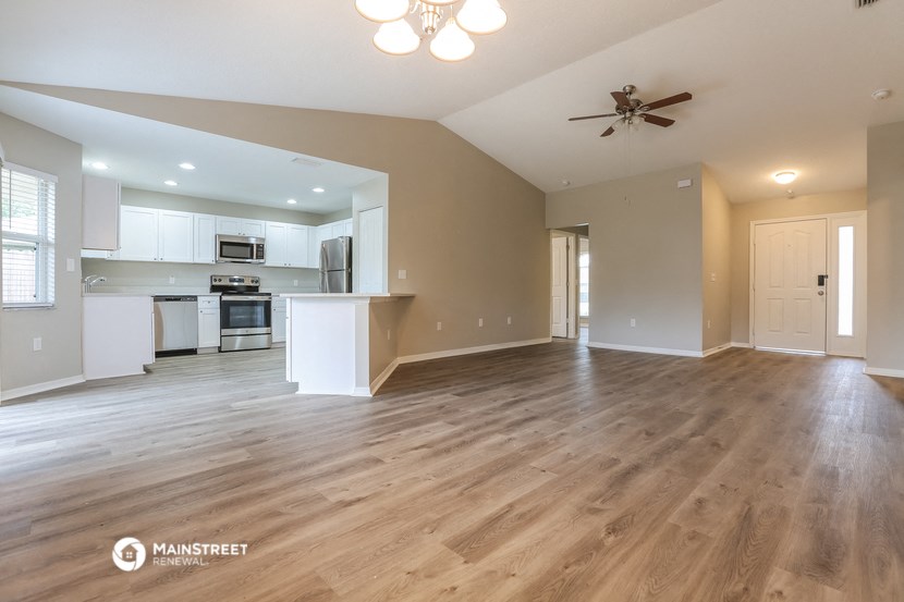 an open living room and kitchen with wood flooring and a ceiling fan