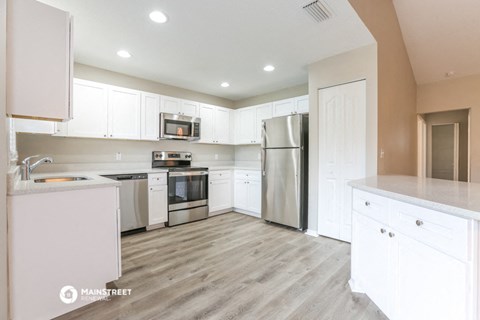 a large kitchen with white cabinets and stainless steel appliances