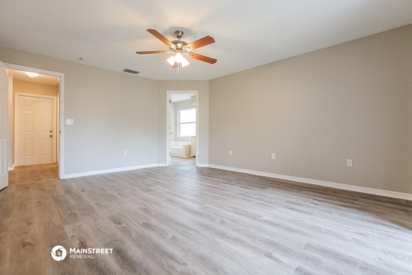the spacious living room with wood floors and a ceiling fan