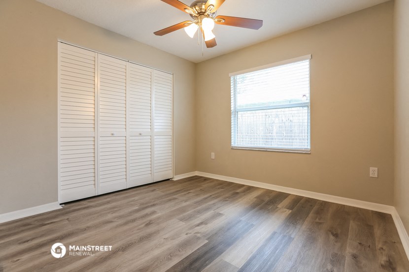 the spacious living room with wood floors and a ceiling fan