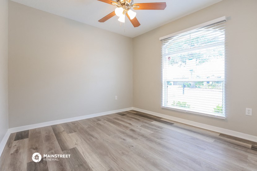 an empty room with a large window and a ceiling fan