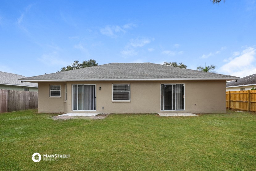 a beige house with a yard and a wooden fence