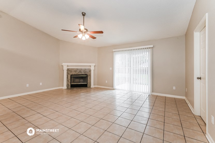 an empty living room with a fireplace and a ceiling fan