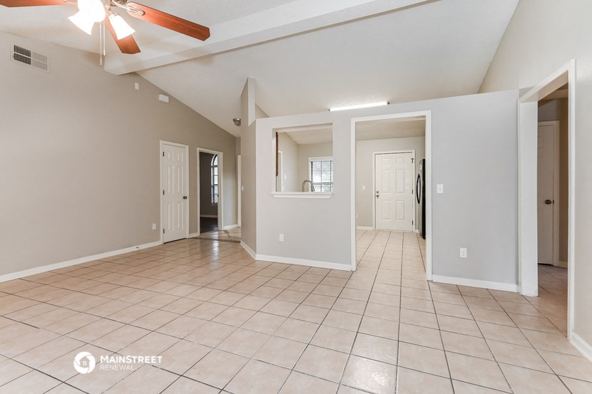 a spacious living room with tile flooring and a ceiling fan
