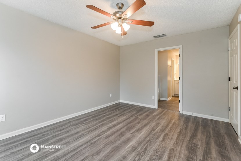 the spacious living room with wood flooring and ceiling fan