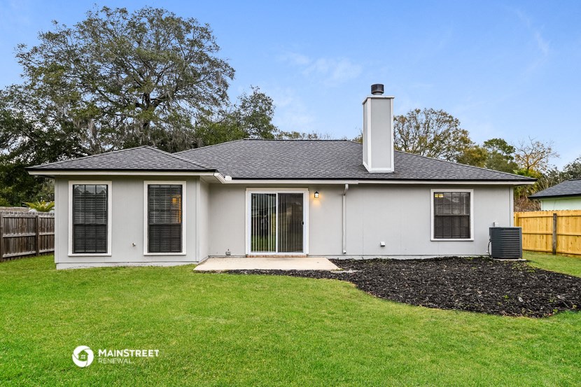 a small white house with a lawn and a backyard