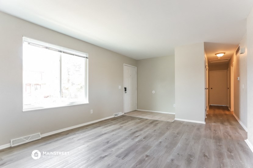 an empty living room with wood floors and a large window