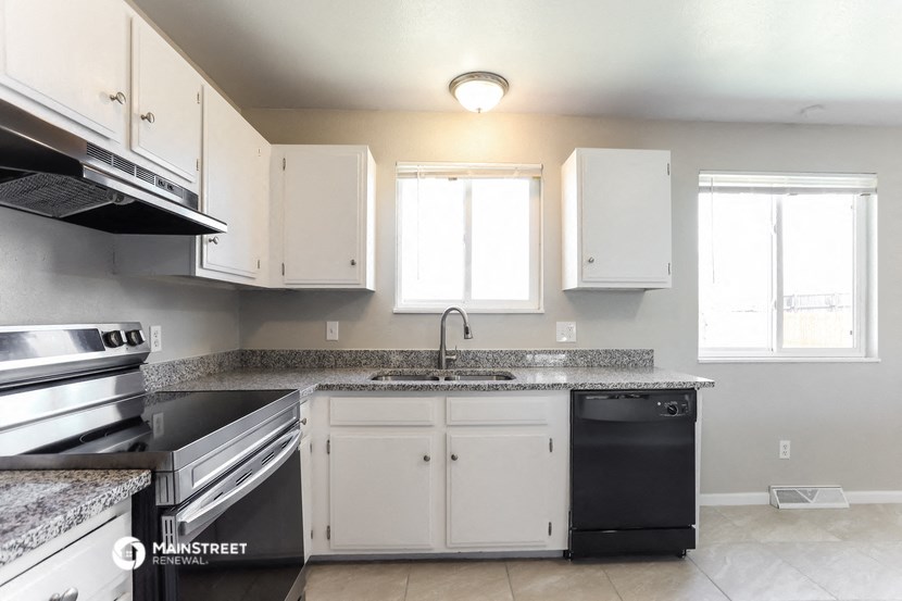 an empty kitchen with white cabinets and granite counter tops