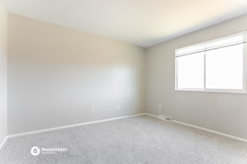 an empty room with a window and carpet