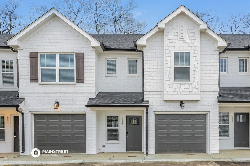 the front of a white house with black garage doors