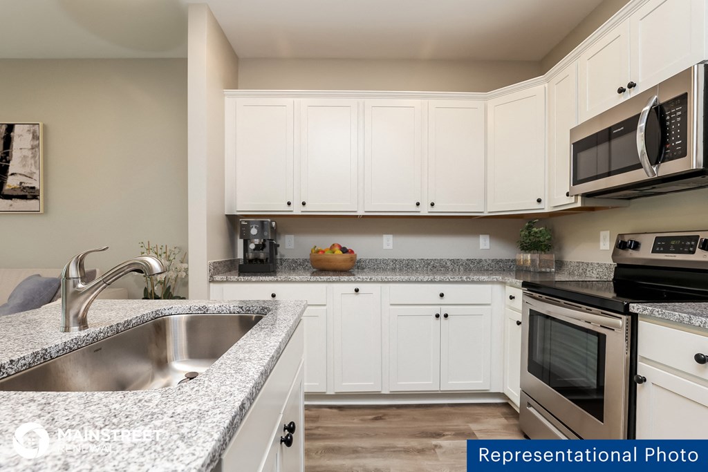 a kitchen with granite counter tops and white cabinets