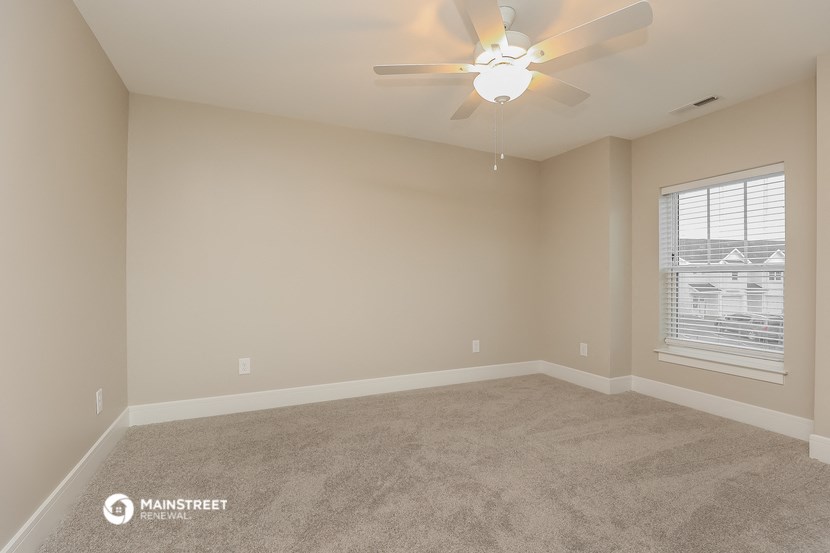 the spacious living room with carpet and a ceiling fan