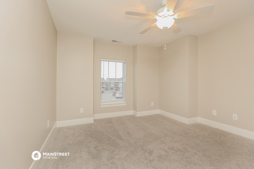 an empty living room with a ceiling fan and a window