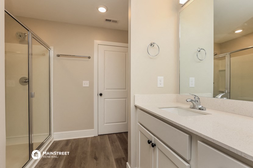 a bathroom with white cabinets and a sink and a shower