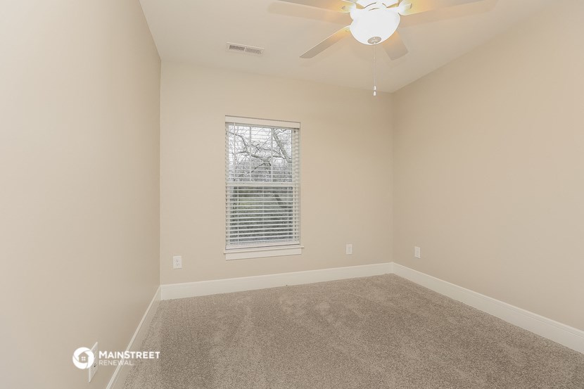 a empty room with a ceiling fan and a window