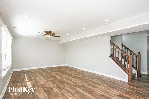 A spacious room with wooden floors and a staircase.