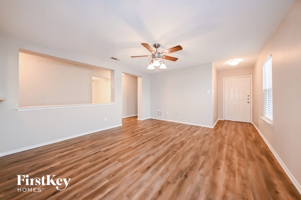 an empty living room with a ceiling fan and a window