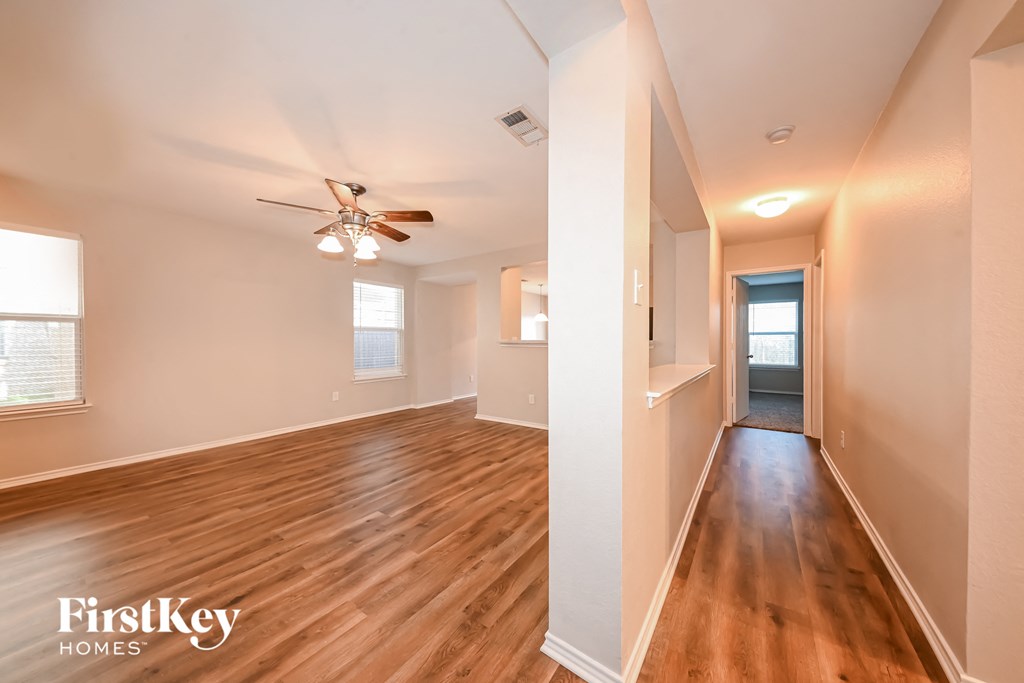 a living room and hallway with wood flooring and a ceiling fan