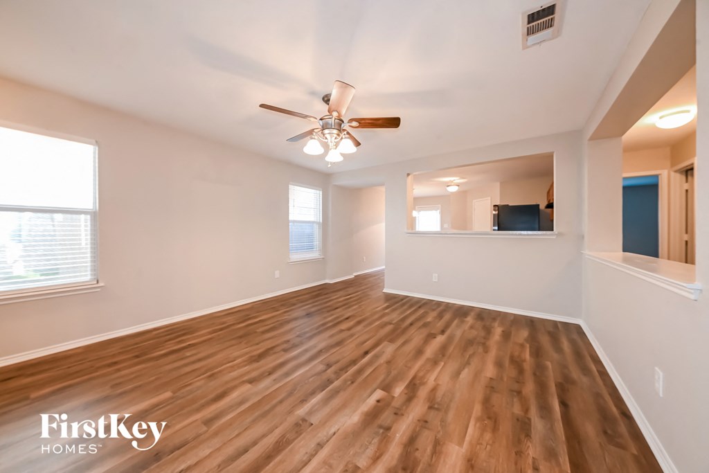 an empty living room with wood flooring and a ceiling fan