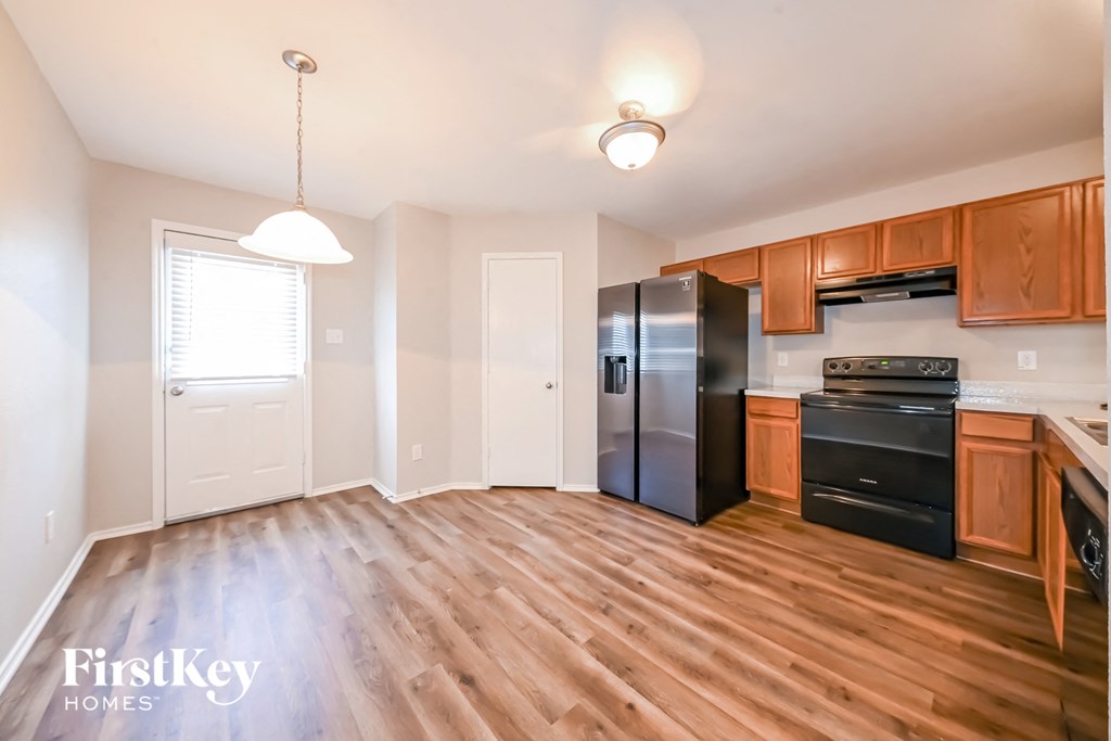 an empty kitchen with wood flooring and black appliances