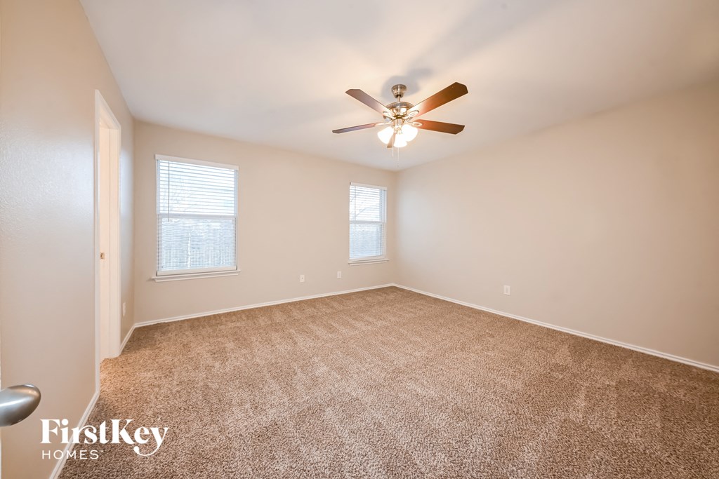a spacious living room with carpet and a ceiling fan