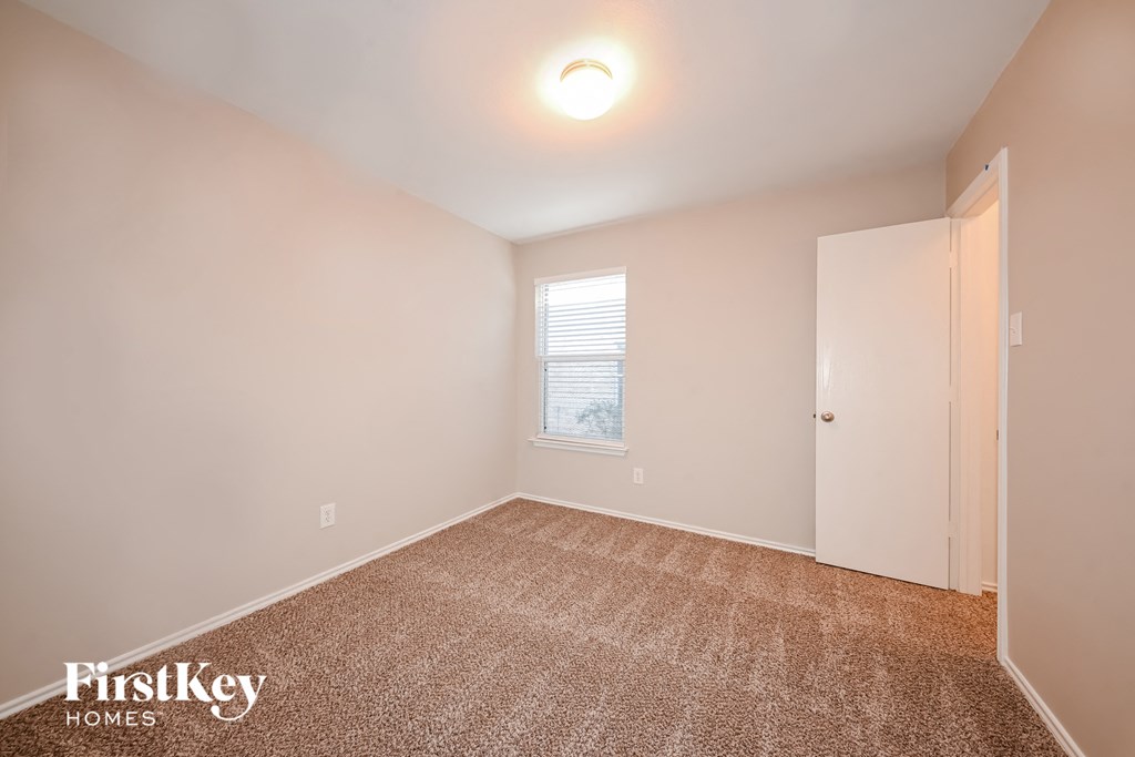 a bedroom with a carpeted floor and white walls and a window