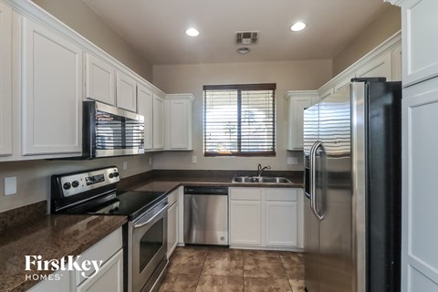 A kitchen with a stove top oven, sink, and refrigerator.