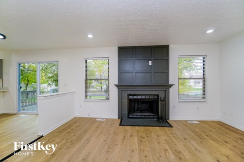 A living room with a fireplace and wooden floors.