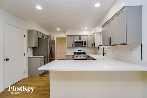 A kitchen with a white counter top and cabinets.