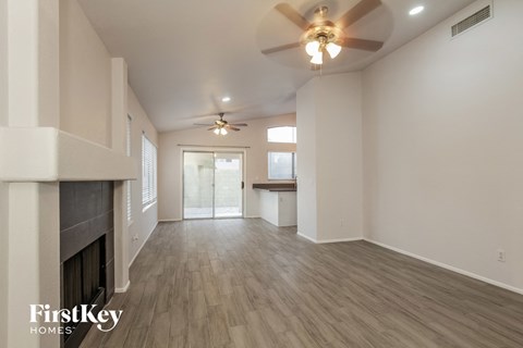 A spacious room with a fireplace and a ceiling fan.