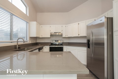 A kitchen with a stainless steel refrigerator and white cabinets.
