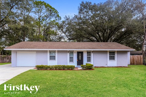 A house with a white front yard and a tree in the background.
