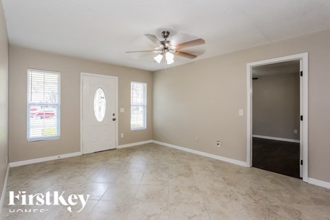 A spacious room with a ceiling fan and two doors.