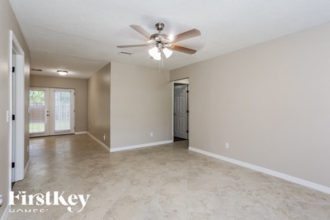 A spacious room with a ceiling fan and tiled flooring.