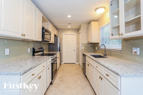 A kitchen with white cabinets and granite countertops.