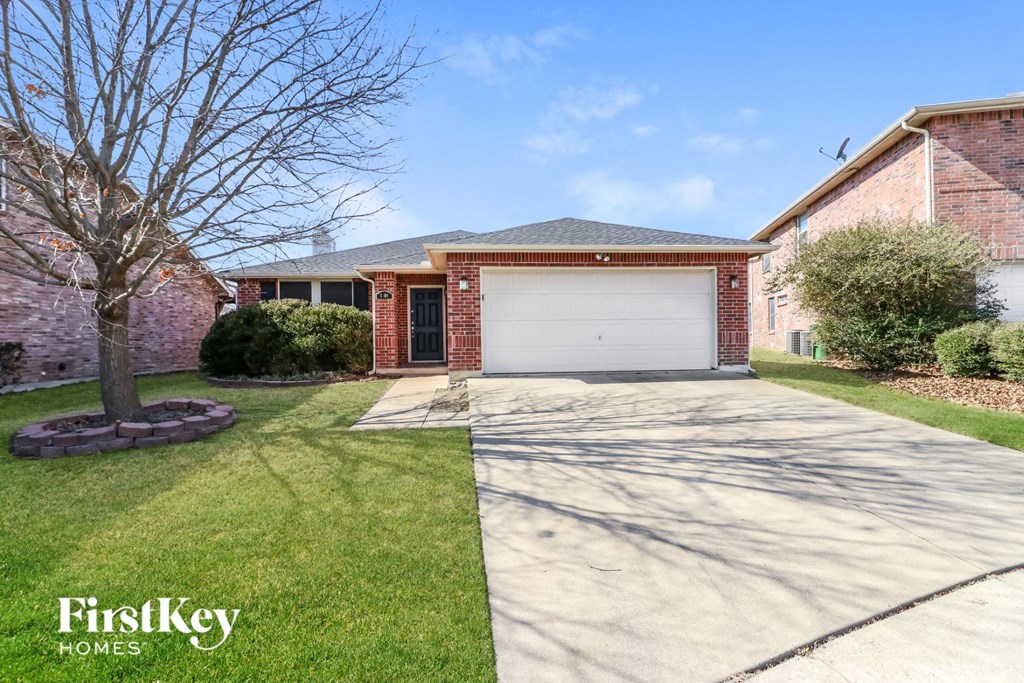 A house with a garage and a tree in the front yard.