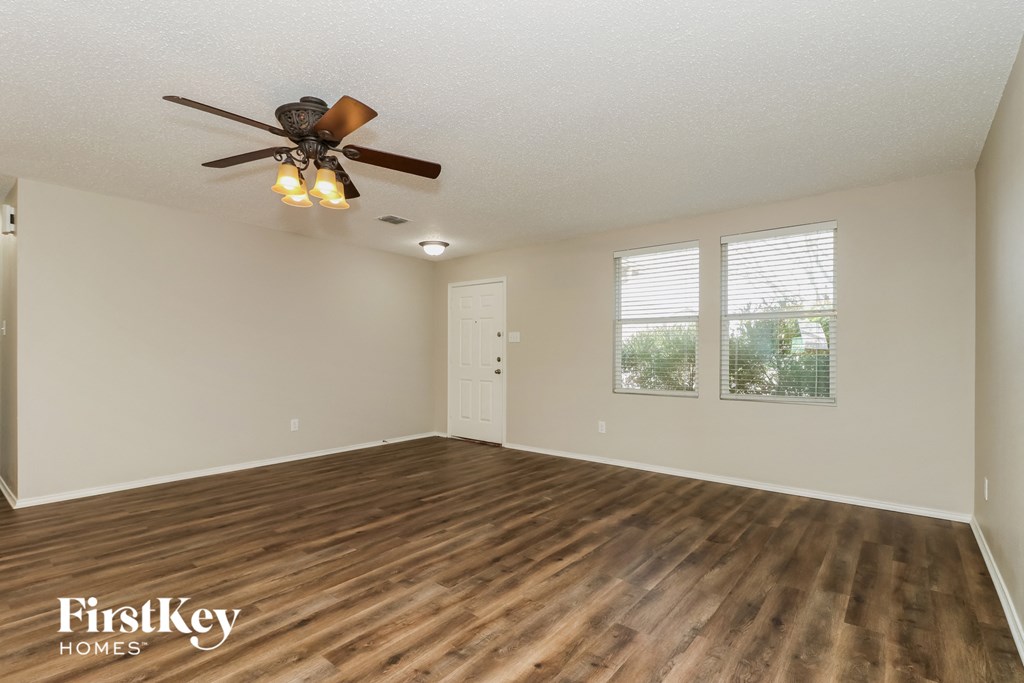 A room with a ceiling fan and wooden flooring.