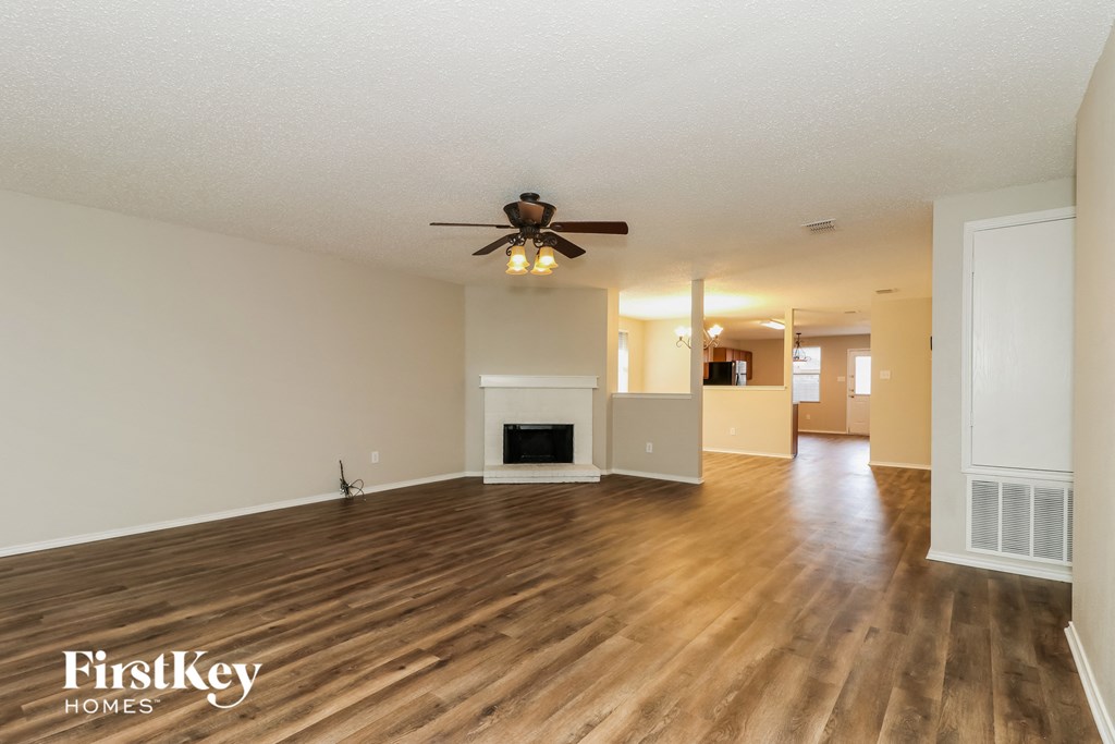 A spacious living room with a fireplace and a ceiling fan.