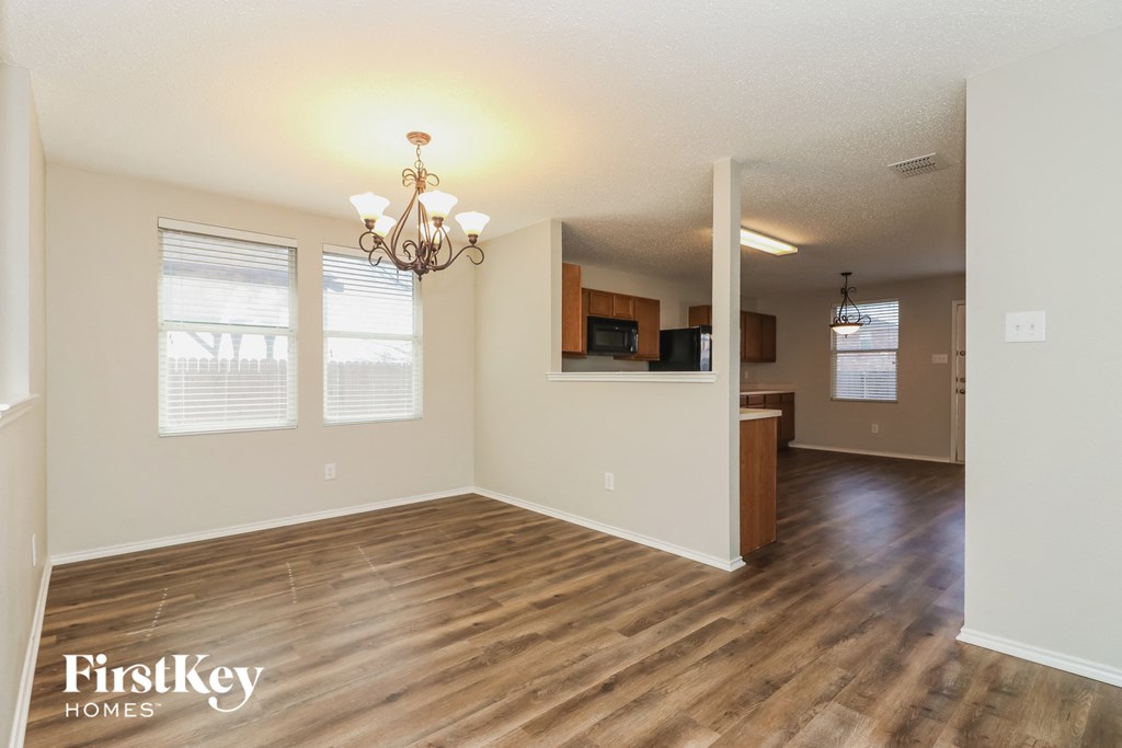 A room with wooden floors and a chandelier is empty and waiting to be furnished.