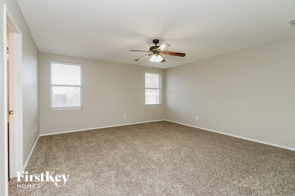 A room with a ceiling fan and two windows.