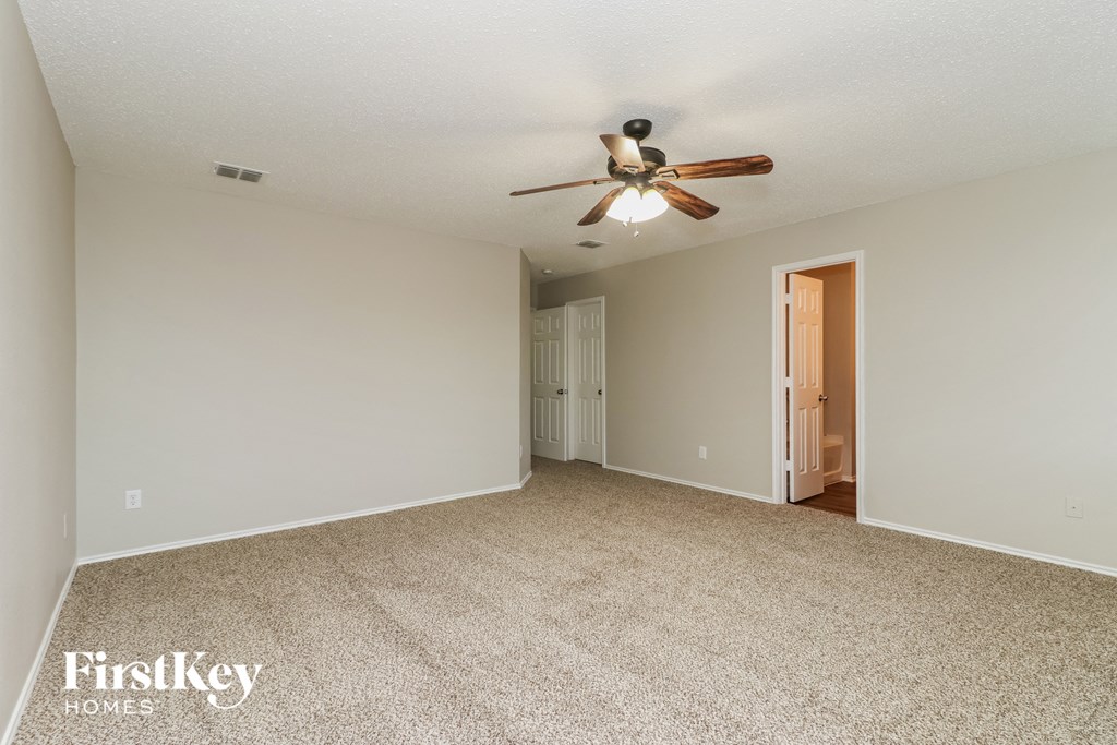 A spacious room with a ceiling fan and carpeted floor.