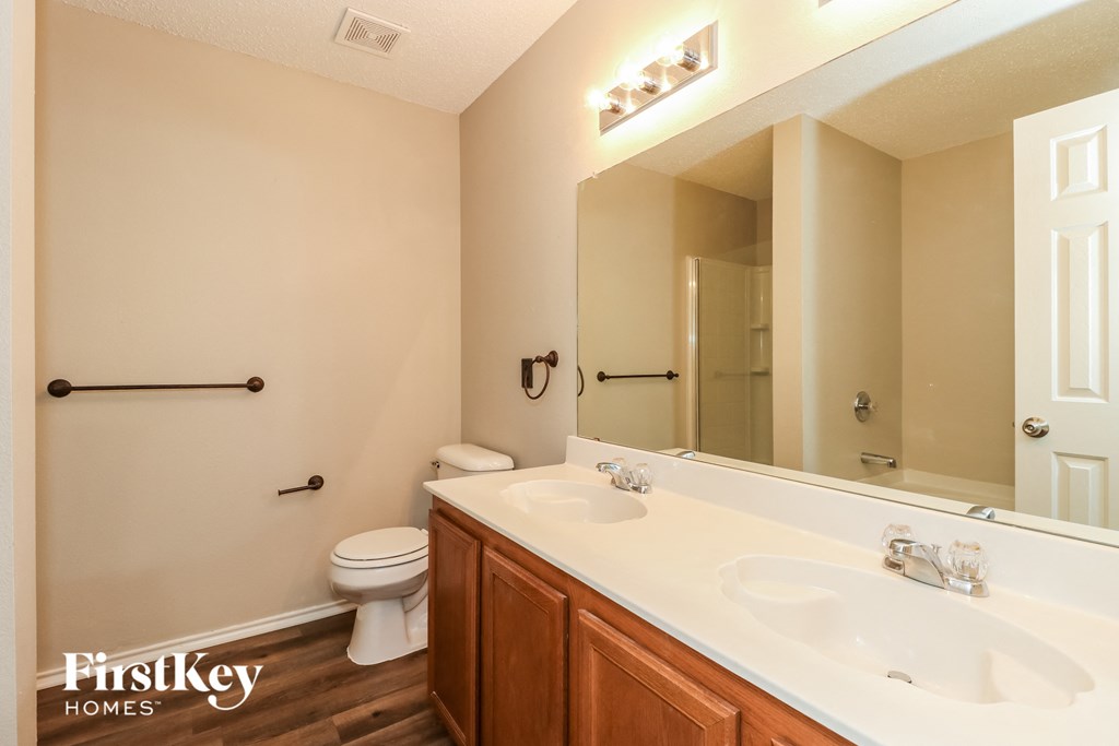 A bathroom with a toilet, sink, and mirror.