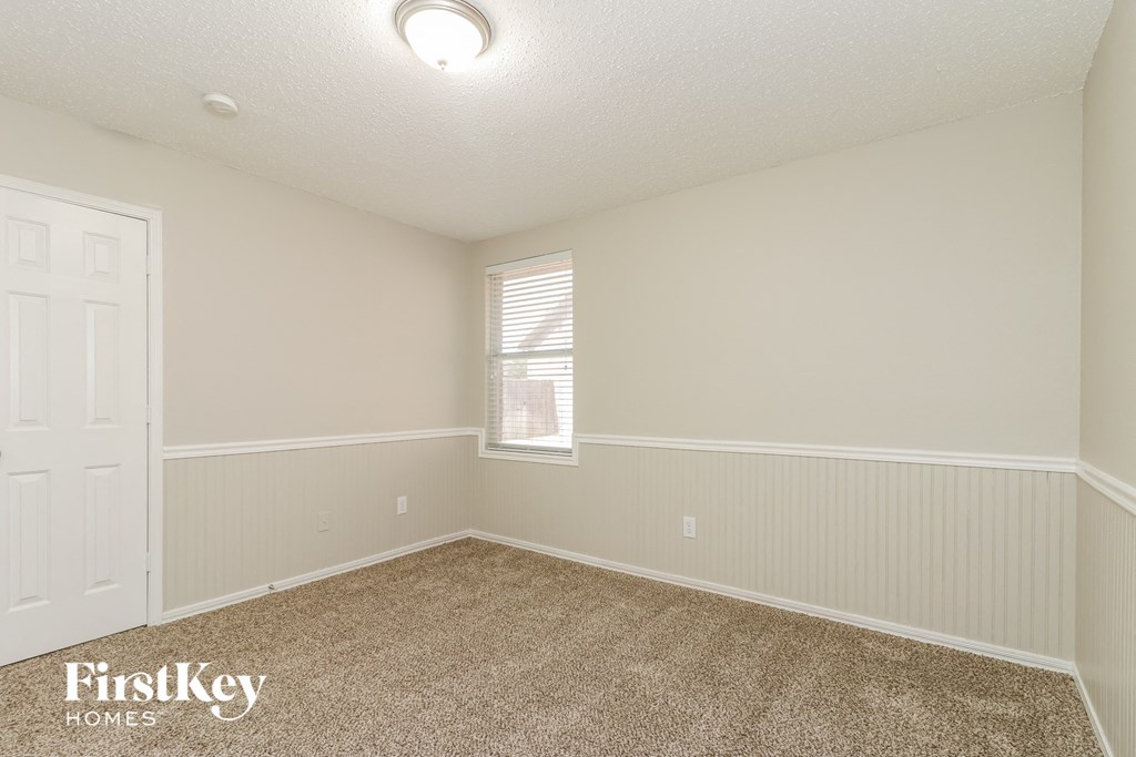 A room with a carpeted floor and a window with blinds.