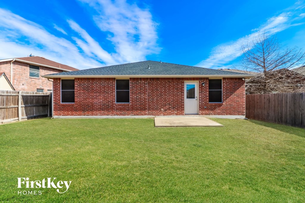 A brick house with a green lawn in front of it.