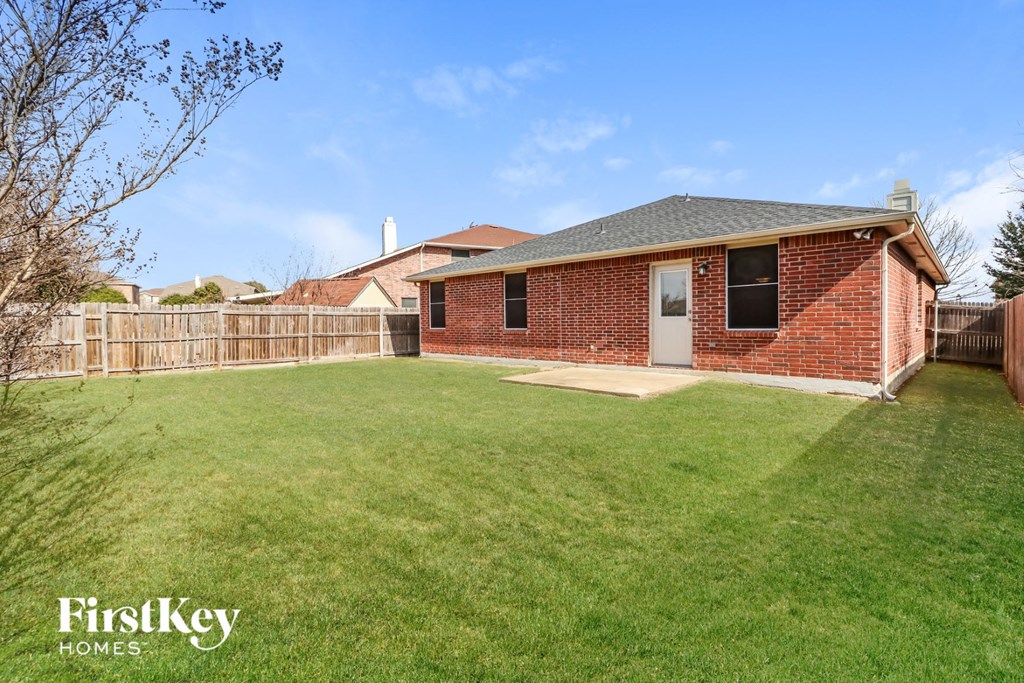 A red brick house with a white door and a green lawn in front.