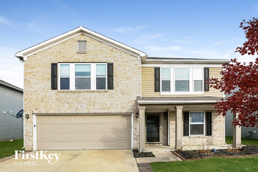 a tan brick house with a white garage door