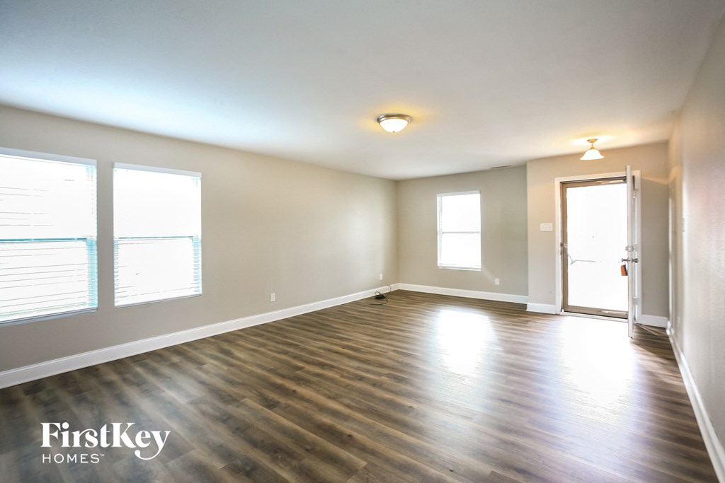 the living room of an empty house with wood floors and white walls