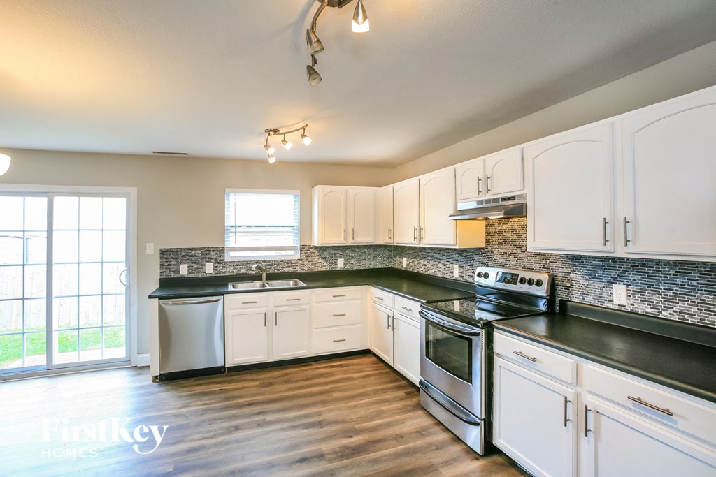 an empty kitchen with white cabinets and black counter tops