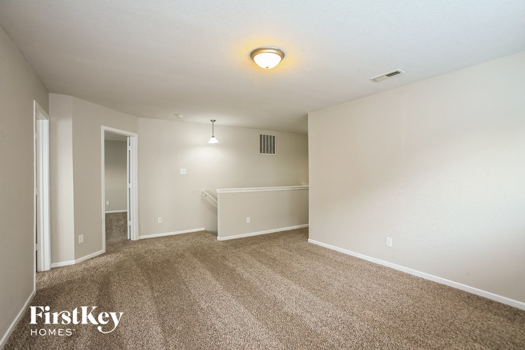 a spacious living room with carpet and white walls